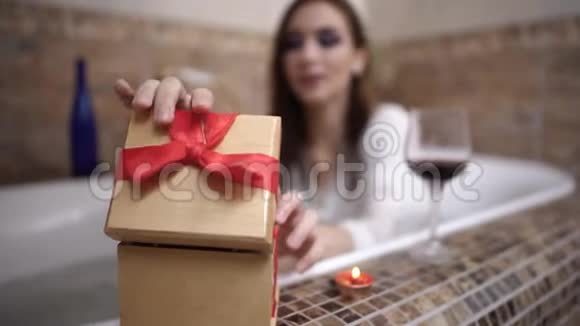 年轻女子打开礼物盒拿着粉红色的小玫瑰洗澡视频的预览图
