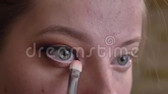 年轻的白种人女化妆师将白色眼影贴在眼角上的特写肖像视频的预览图