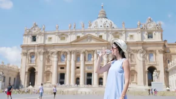 年轻女子在炎热的日子里喝水的背景圣彼得大教堂在梵蒂冈城罗马意大利视频的预览图