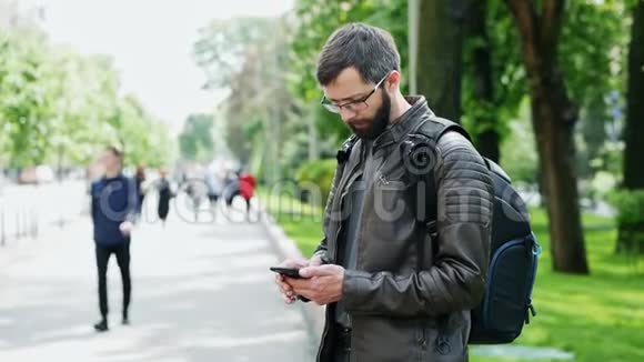 带包的胡子男人在街上用手机视频的预览图