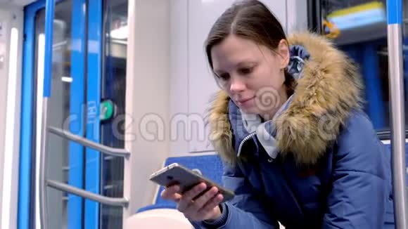 疲惫的女人坐在空的地铁车上浏览她的智能手机的肖像前景视频的预览图
