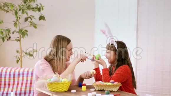 妈妈和女儿手里拿着一个装饰好的鸡蛋我女儿试着把刷子碰到妈妈的鼻子上但是视频的预览图