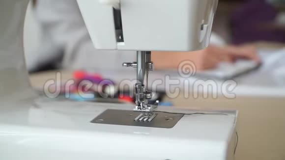 裁缝坐在工作室的一张桌子旁边的缝纫机上为未来的服装绘制草图视频的预览图
