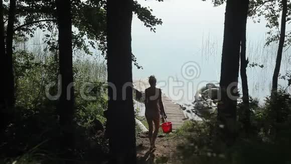 一个穿泳衣的女人手里拿着水桶在一个木墩上视频的预览图