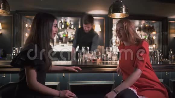 年轻女孩在酒吧里谈笑风生在酒吧里微笑着调酒师做鸡尾酒视频的预览图