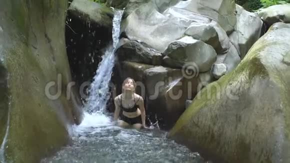 个动作缓慢的迷人女孩溅起清澈的湖水看着用绿色的小瀑布拍摄视频的预览图
