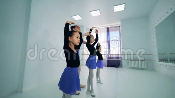 女孩们正在和一位女教练练习芭蕾姿势视频的预览图