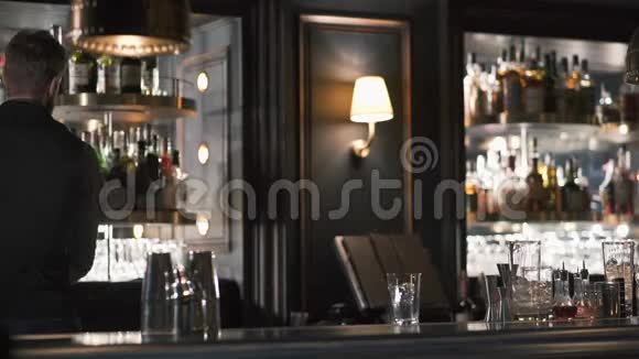 调酒师滚动圆形架子选择必要的酒精酒吧老板用瓶子做鸡尾酒视频的预览图