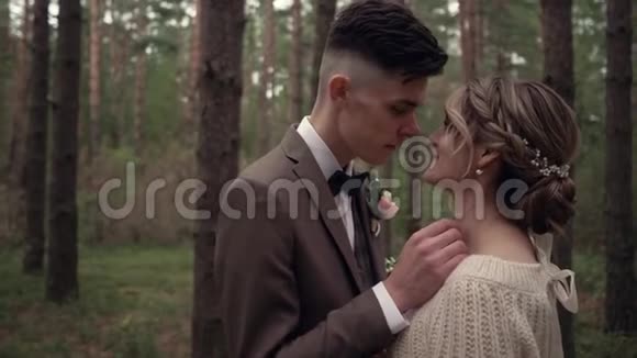 美丽的森林里美丽的年轻婚礼夫妇拥抱亲吻和微笑视频的预览图