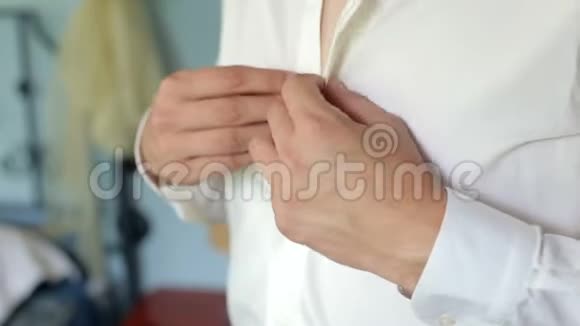 男人把他的白色衬衫扣在明亮的窗户前特写视频的预览图