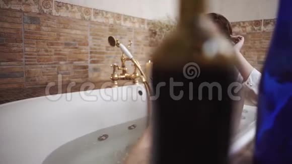 两个空瓶从酒精是在边缘的浴缸关闭悲伤的女人坐在浴室里两瓶酒视频的预览图