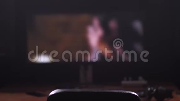 一部亲密的电影在大屏幕上一个长着黑色头发的家伙走进相框戴上耳机看着一个人视频的预览图