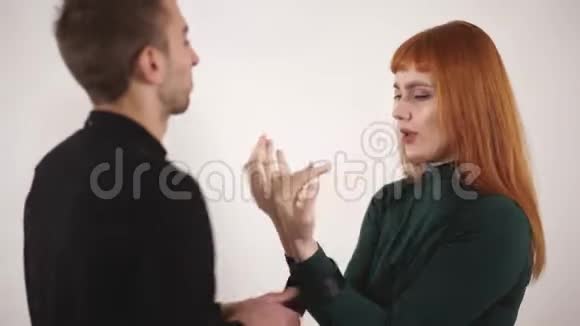 愤怒的男人大吼大叫年轻的女人长着红色的长发用皮带系着雌性的手露出他的腰带视频的预览图