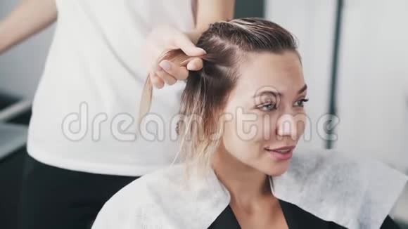 把理发师的手贴在年轻女性的头发上视频的预览图