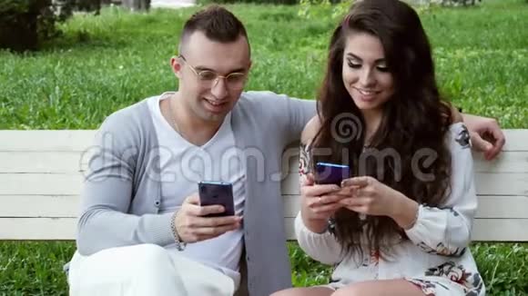 美丽的一对夫妇在公园的长椅上使用电话在网上购物视频的预览图