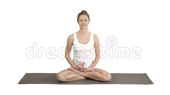 美丽的女人穿着白色的衣服坐在瑜伽垫上在白色的背景上和相机交谈视频的预览图