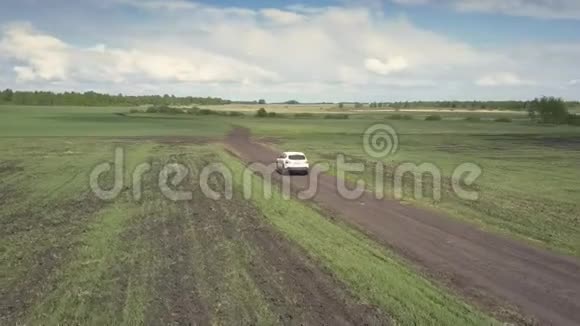 鸟瞰一望无际的田野和白色汽车在地面道路上视频的预览图