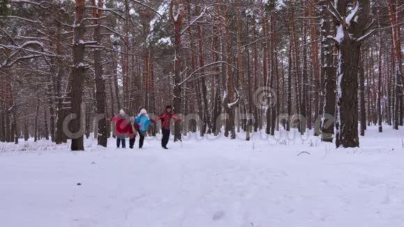 快乐的父母和孩子在针叶林公园沿着雪的冬天的道路奔跑在冬天寒冷的日子笑家庭游戏视频的预览图