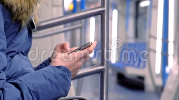 女人坐在一辆空的地铁车里在她的智能手机上看视频侧视双手特写视频的预览图