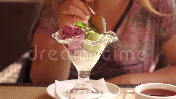 一个女孩在街头咖啡馆里用漂亮的玻璃吃冰淇淋视频的预览图