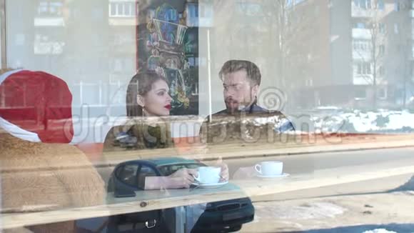一对夫妇坐在咖啡店喝咖啡透过窗户看到视频的预览图