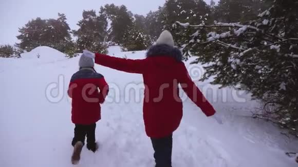 在寒冷的冬天快乐的孩子们在松林公园里沿着下雪的冬天的路跑步是很有趣的青少年玩追赶游戏视频的预览图