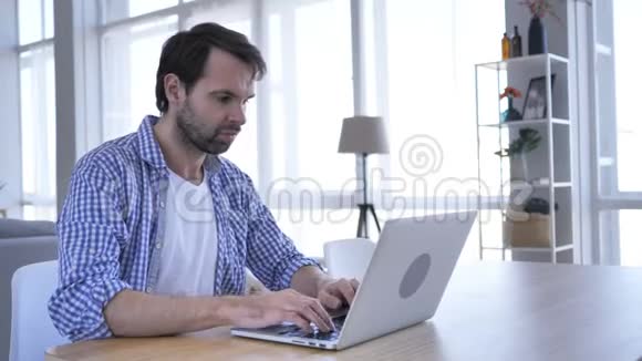 愤怒的休闲胡须男在办公室工作手提电脑视频的预览图