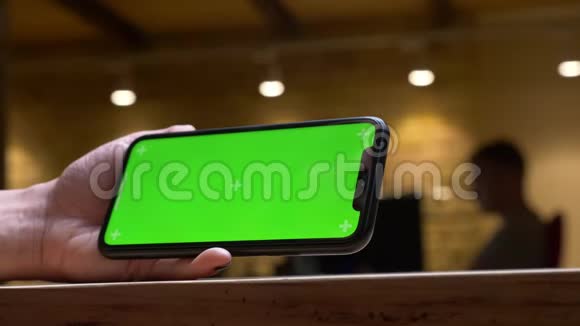特写后视镜头女性手在手机上播放视频绿色的彩色屏幕水平地握着它视频的预览图