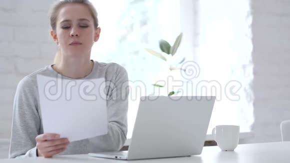 青年妇女阅读文件及手提电脑工作视频的预览图