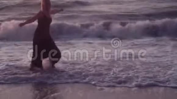 一个穿黑衣服的女人向她身边跑去拥抱的手臂在海上在巨浪中视频的预览图