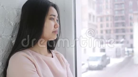 年轻的亚洲女人打哈欠坐在窗前视频的预览图