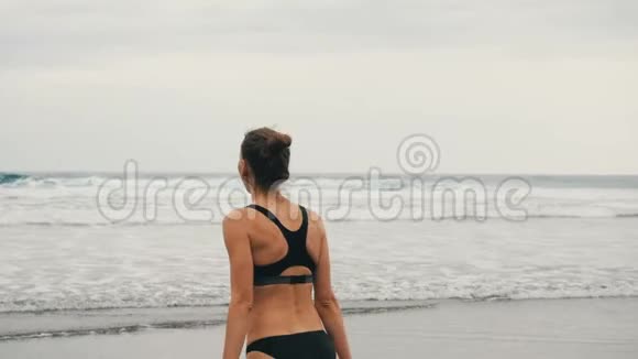 追踪在加那利群岛特内里费的黑色沙滩上慢跑的迷人年轻女子的照片多云的女性视频的预览图