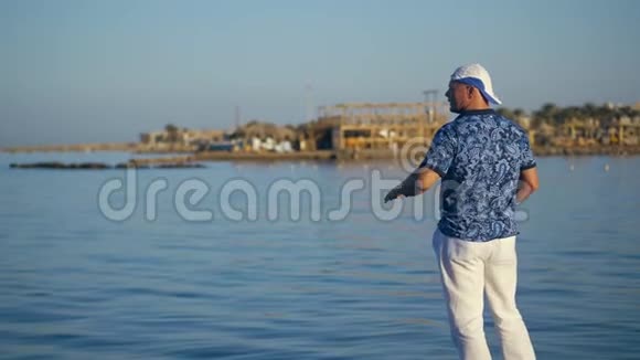 岸上的一个人用手向海上游艇上的人展示一些东西海滩上的人挥舞着他的手臂滨海湾视频的预览图