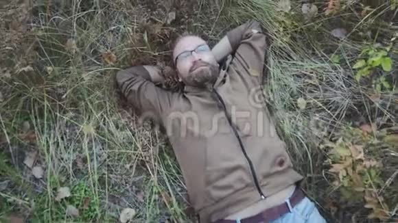 一个年轻快乐的人在草地上放松的肖像双手放在头下视频的预览图