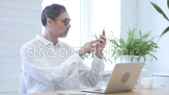 中年男子在工作时在线视频聊天在智能手机上聊天视频的预览图