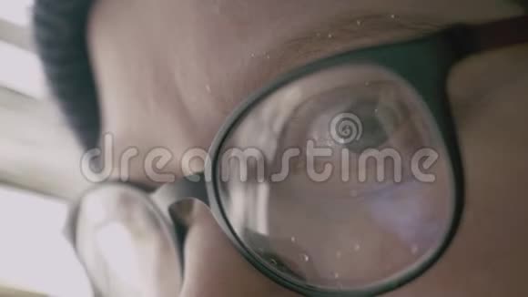 眼镜中女性眼睛的特写镜头反映了智能手机屏幕视频的预览图
