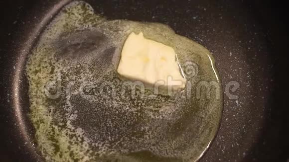 一块黄油在热炒锅中融化用来烤和炒蔬菜视频的预览图