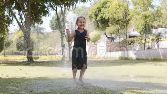 快乐的女孩正在公园里的喷水下跳进水坑里视频的预览图