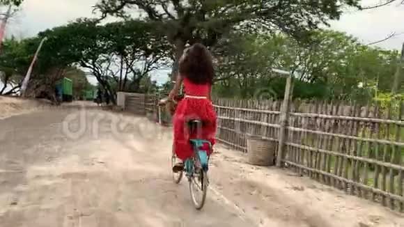 在热带度假村背景的乡间小路上骑自行车的女人视频的预览图