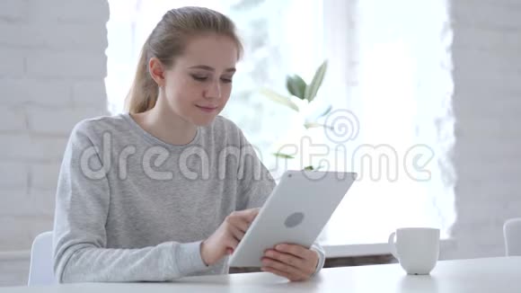 年轻女性在使用平板电脑时庆祝成功视频的预览图