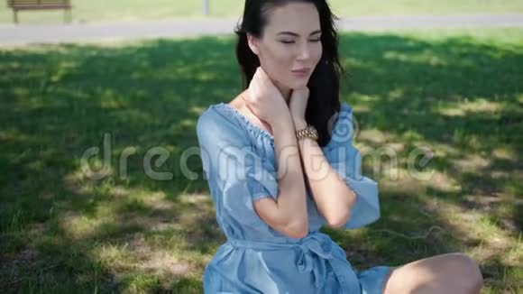 一幅漂亮的黑发女人坐在公园里的蓝色裙子视频的预览图