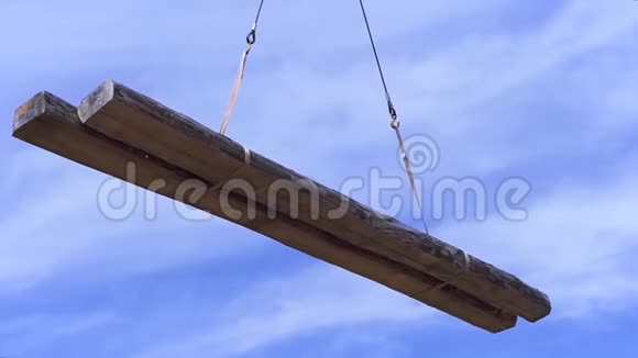 两根木梁由吊车在蓝色多云的天空背景上运输剪辑空中原木的底部视图视频的预览图