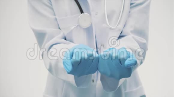 幸福的年轻微笑女孩医生的肖像穿着白色长袍和蓝色手套把药拿在手里视频的预览图