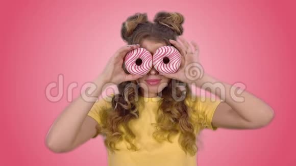 一个穿着黄色衬衫拿着甜甜圈摆姿势的漂亮女孩闭上眼睛微笑着看着镜头视频的预览图