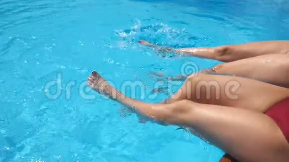 女腿在酒店的游泳池里溅出晶莹剔透的水两个朋友坐在盆边尽情享受视频的预览图