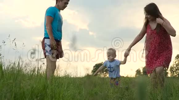 快乐的一家人在日落时在夏天的绿色田野里玩得很开心慢动作视频的预览图