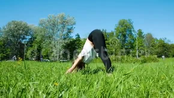 女孩在大自然中从事健身活动女孩体操运动员在城市公园里抬起腿慢动作视频的预览图