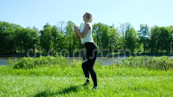 运动女孩在大自然中进行热身跳跃和泵腿肌肉慢动作视频的预览图