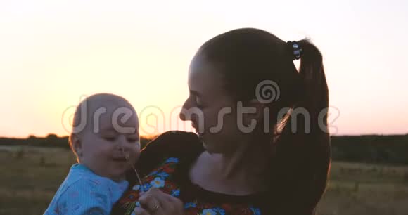 微笑的年轻母亲和她的孩子享受生活在一个田野在日落在斯洛文尼亚视频的预览图
