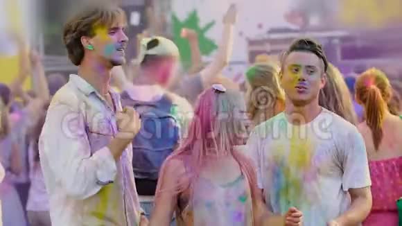 年轻的男男女女被霍利节日的色彩所覆盖随着音乐起舞慢悠悠视频的预览图